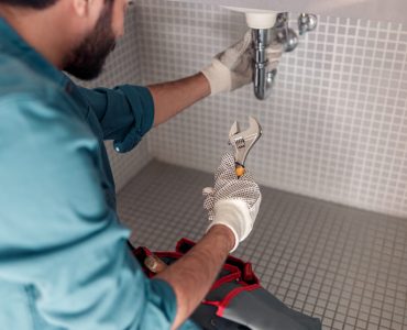 Handyman is repairing faucet of a sink at bathroom. Maintenance and household assistance concept