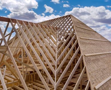 Panorama top view of closeup new wooden roof beams built home under construction under framing with construction site