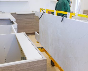 Workers lifting and installing with maple granite counter in kitchen cabinets